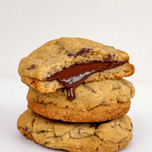 3 stacked cookies. The top cookie is broken in half displaying Nutella chocolate oozing out of the inside